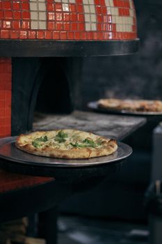 Artisan pizza fresh from a wood-fired oven with aromatic herbs and golden crust.