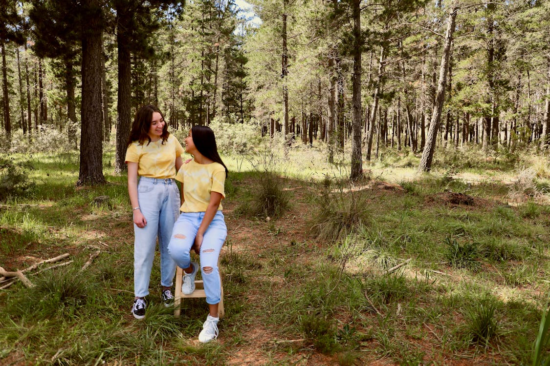 Girls Wearing Yellow T-Shirts and Jeans Smiling in a Forest