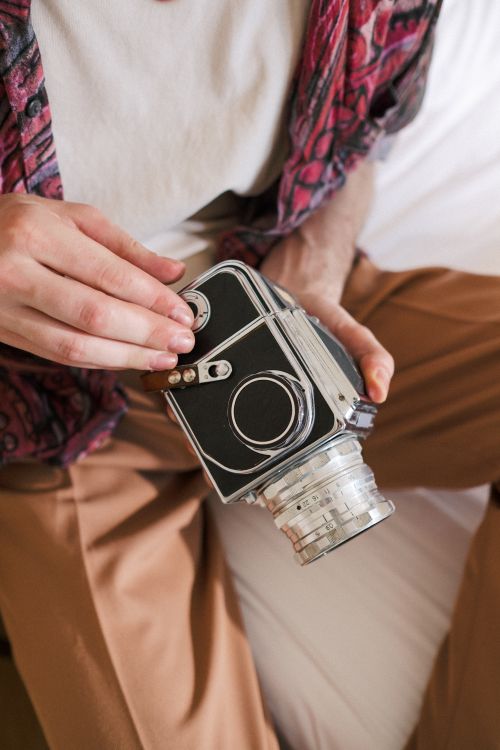Free Close-up of a vintage camera held by an unrecognizable person sitting indoors. Stock Photo