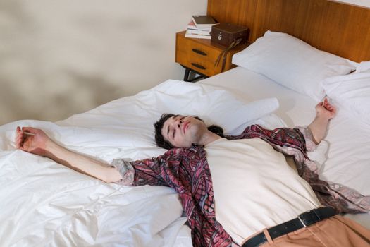 Young Man Laying on Back in Bed and Chilling Out