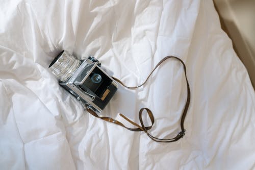 Analog Camera Laying on Undone Bed