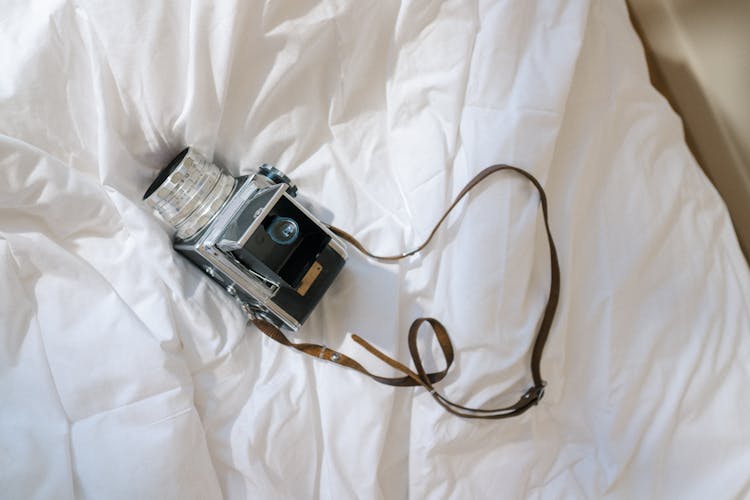 Analog Camera Laying On Undone Bed