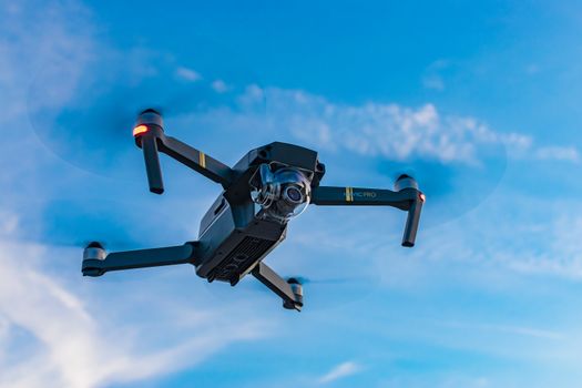 A sleek drone captured mid-air against a bright blue sky, showcasing advanced technology.