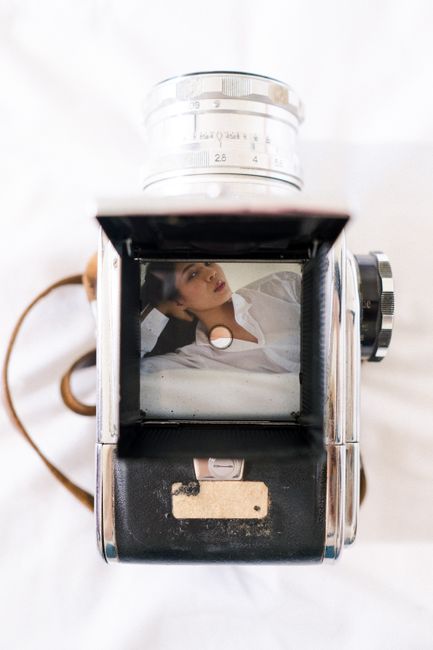 Vintage camera viewfinder reflecting a woman's portrait with a white background.