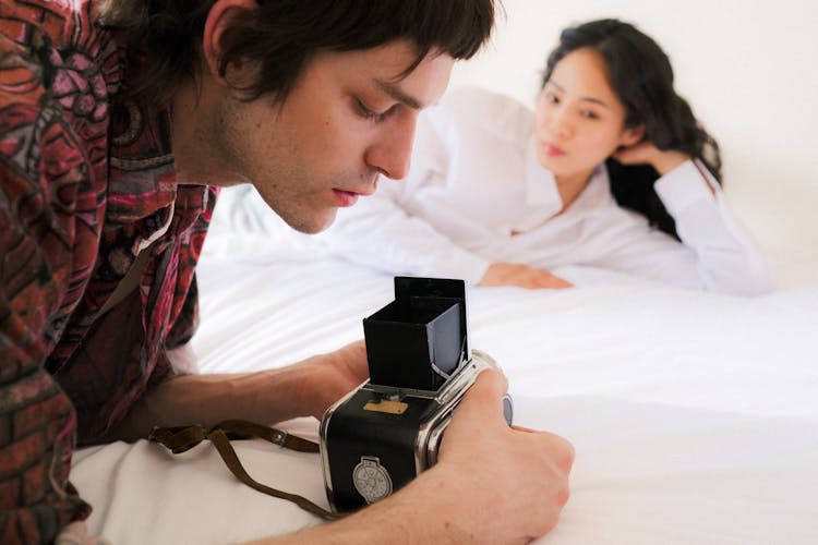 Man Setting Up The Camera And Woman Posing