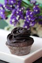 浓郁的巧克力纸杯蛋糕，以花卉为背景，上面涂有奶油糖霜