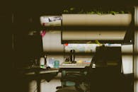 在柔和的灯光下，光线昏暗的办公隔间里配有电脑、椅子、桌子和室内植物