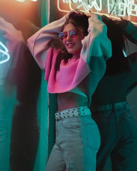 Fashionable woman posing with neon lights in Moscow, showcasing urban street style.