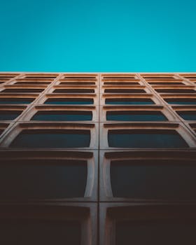 现代建筑的几何立面上，网格状图案映衬着充满活力的蓝天