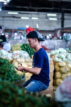 Asian vendor sorting fresh vegetables in an Indonesian market. Captured indoors.