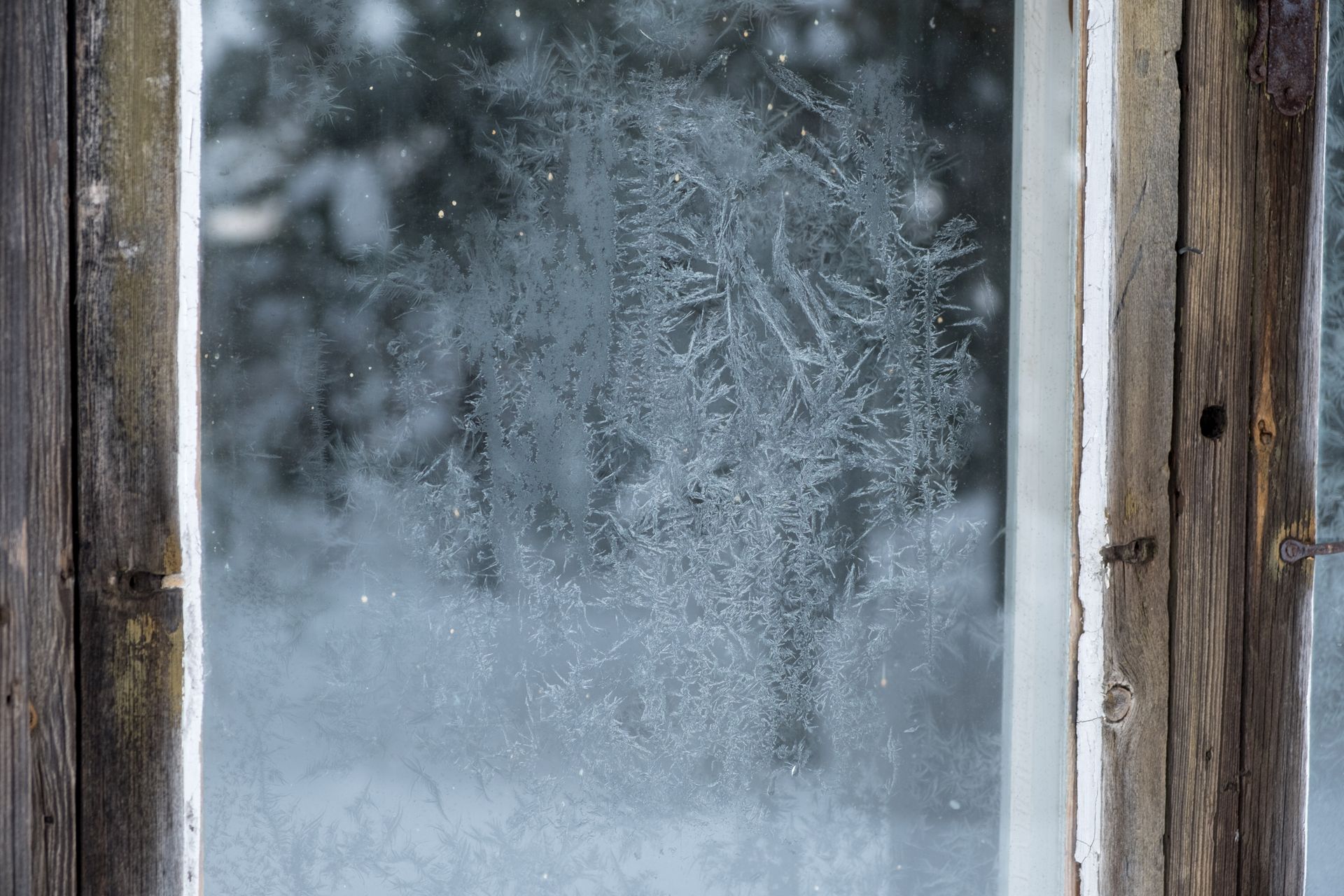 A rustic window showing frosty glass and snow outside, captured in winter season.