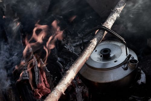 Free A kettle boiling over a warm campfire, perfect for camping enthusiasts. Stock Photo
