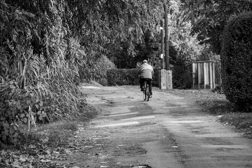 Free Grayscale Photo of a Man Riding a Bicycle on the Road Stock Photo