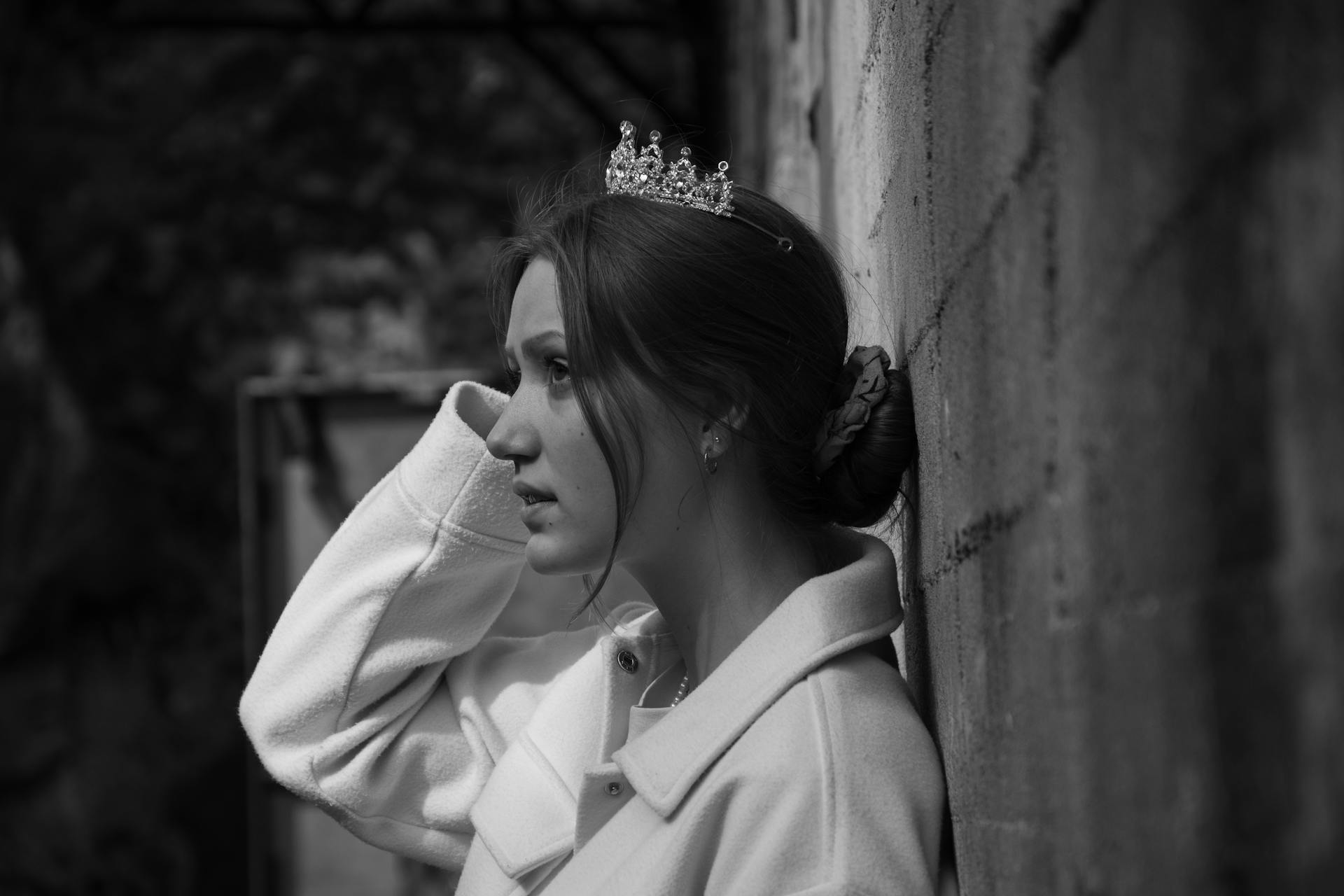 A Woman Wearing Crown on Her Head Leaning on a Wall while Looking Afar