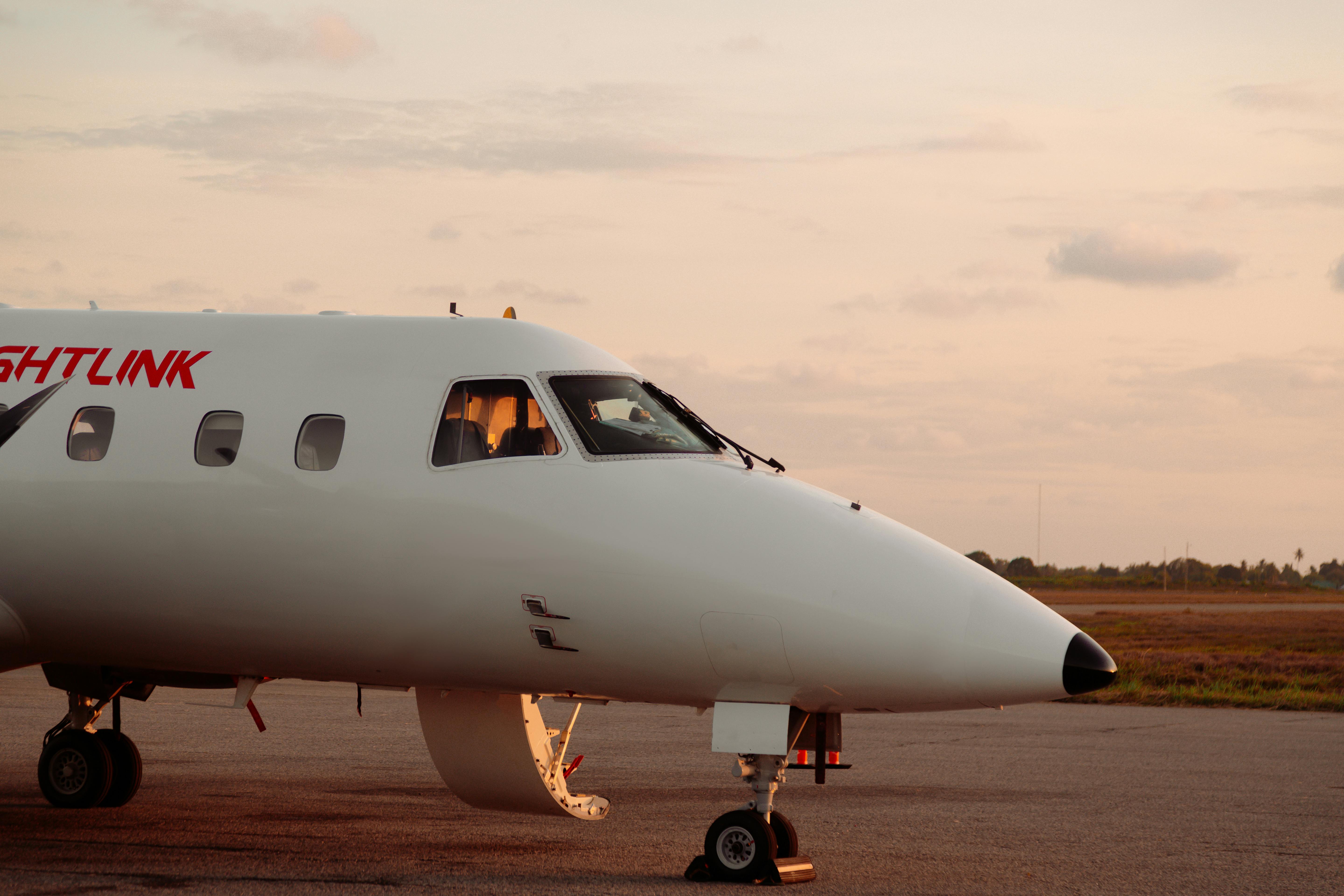 A sleek private jet parked on a runway with a beautiful sunset backdrop.