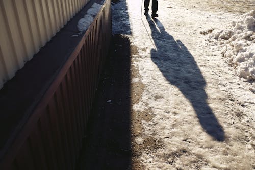 Shadow of Person Walking on Snow Covered Ground 