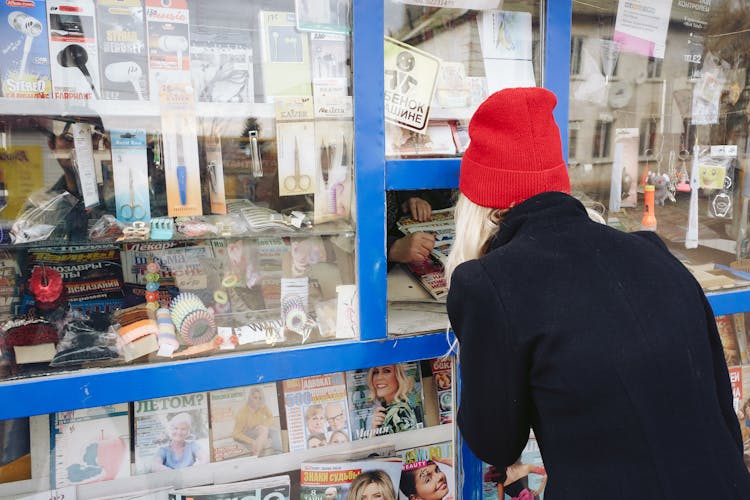 Woman Buying A Newspaper In A Kiosk 