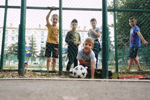A group of boys playing with a soccer ball outdoors at a playground.