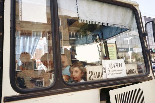 Free A child looks out the window of a public bus, reflecting urban life. Stock Photo