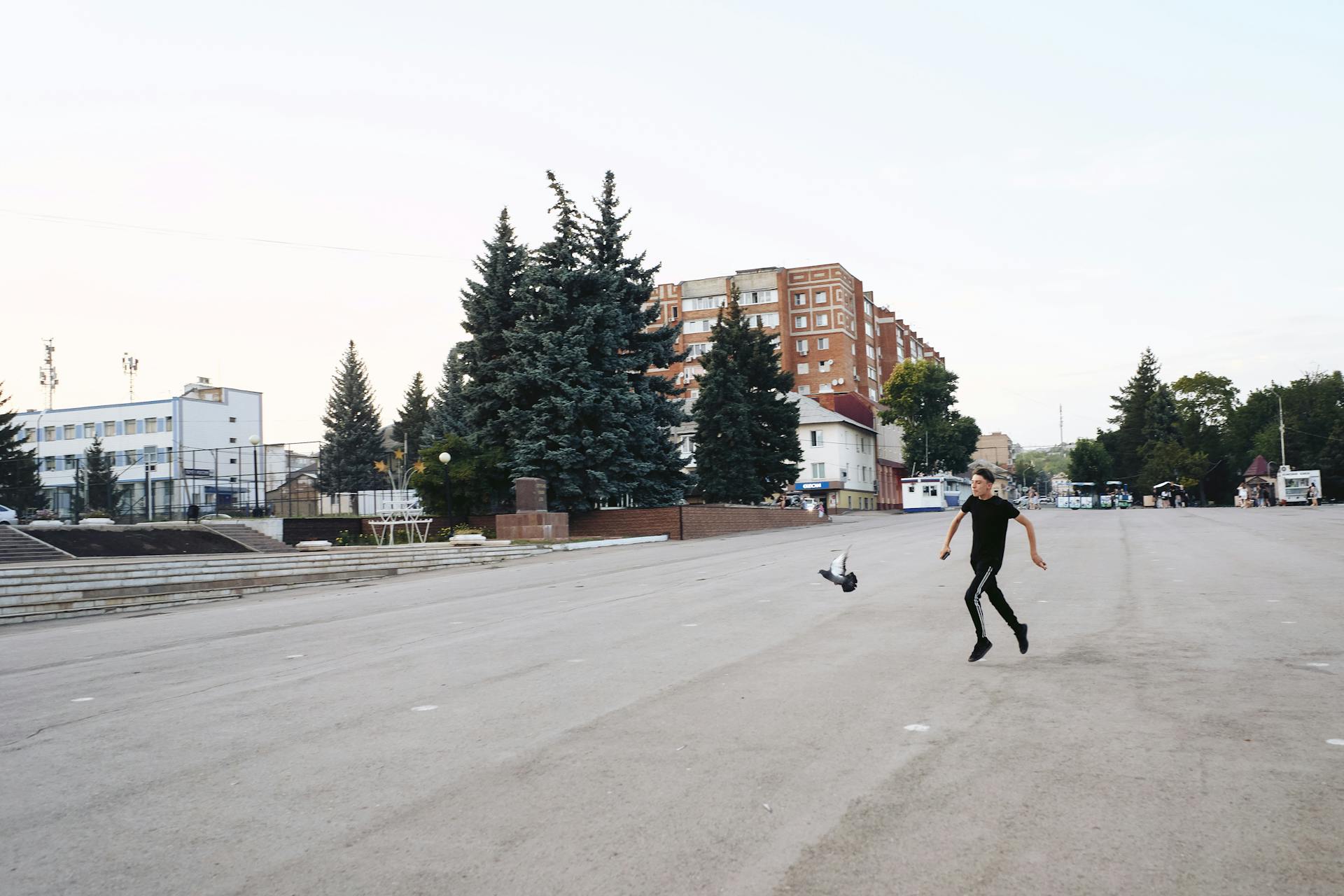 A young man runs beside an expansive urban space on a clear day.