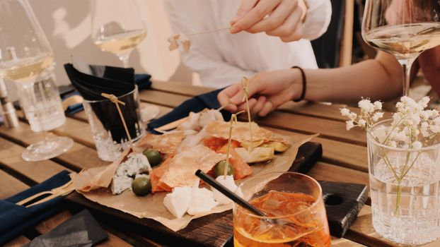 Enjoy a casual meal with wine, cheese, and snacks at an outdoor restaurant setting.