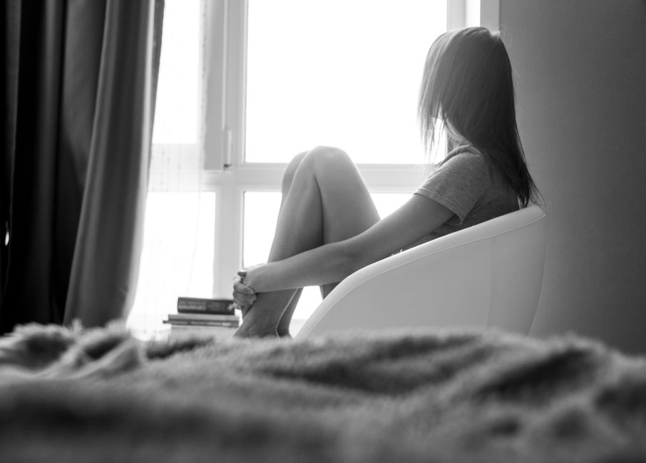 밝은 창가에 의자에 앉아 있는 사색적인 여성.
