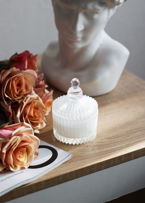 Free Aesthetic arrangement of tea roses, a bust, and a glass jar on a wooden surface. Stock Photo