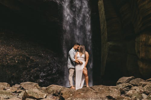 Photo of a Couple Standing in Front of a Waterfall