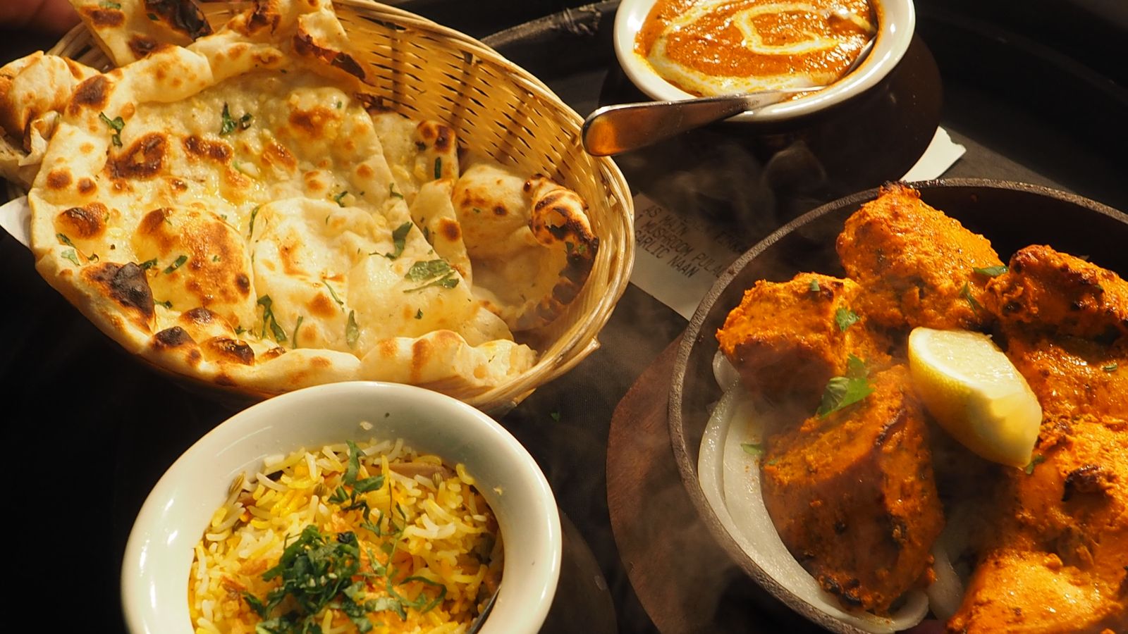 Naan, rice and curry dishes on a table after an Indian takeaway