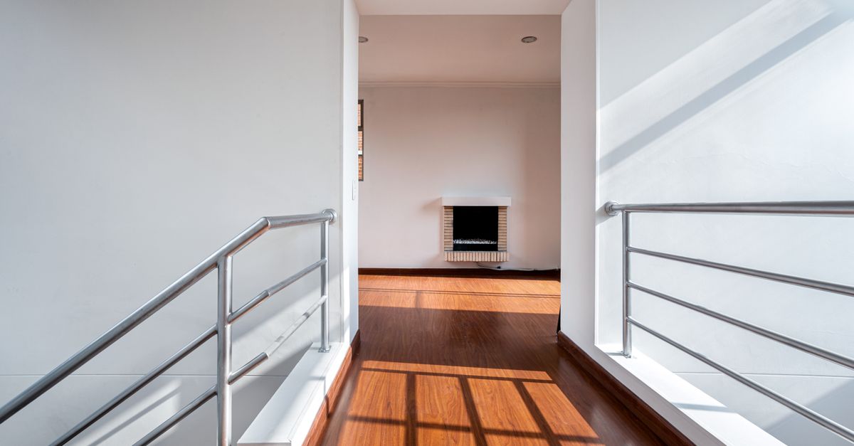 Bright and minimalistic hallway with railings and wooden floor in Bogotá apartment.