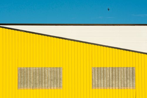 Free Bright yellow industrial building facade with a blue sky background. Stock Photo