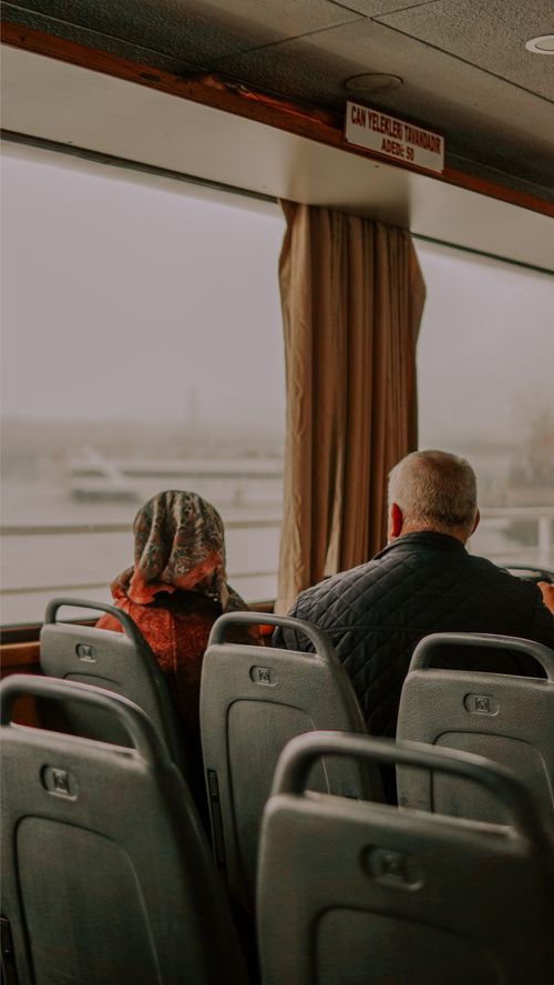 Free A couple sits quietly in a bus overlooking a foggy landscape, creating a serene atmosphere. Stock Photo