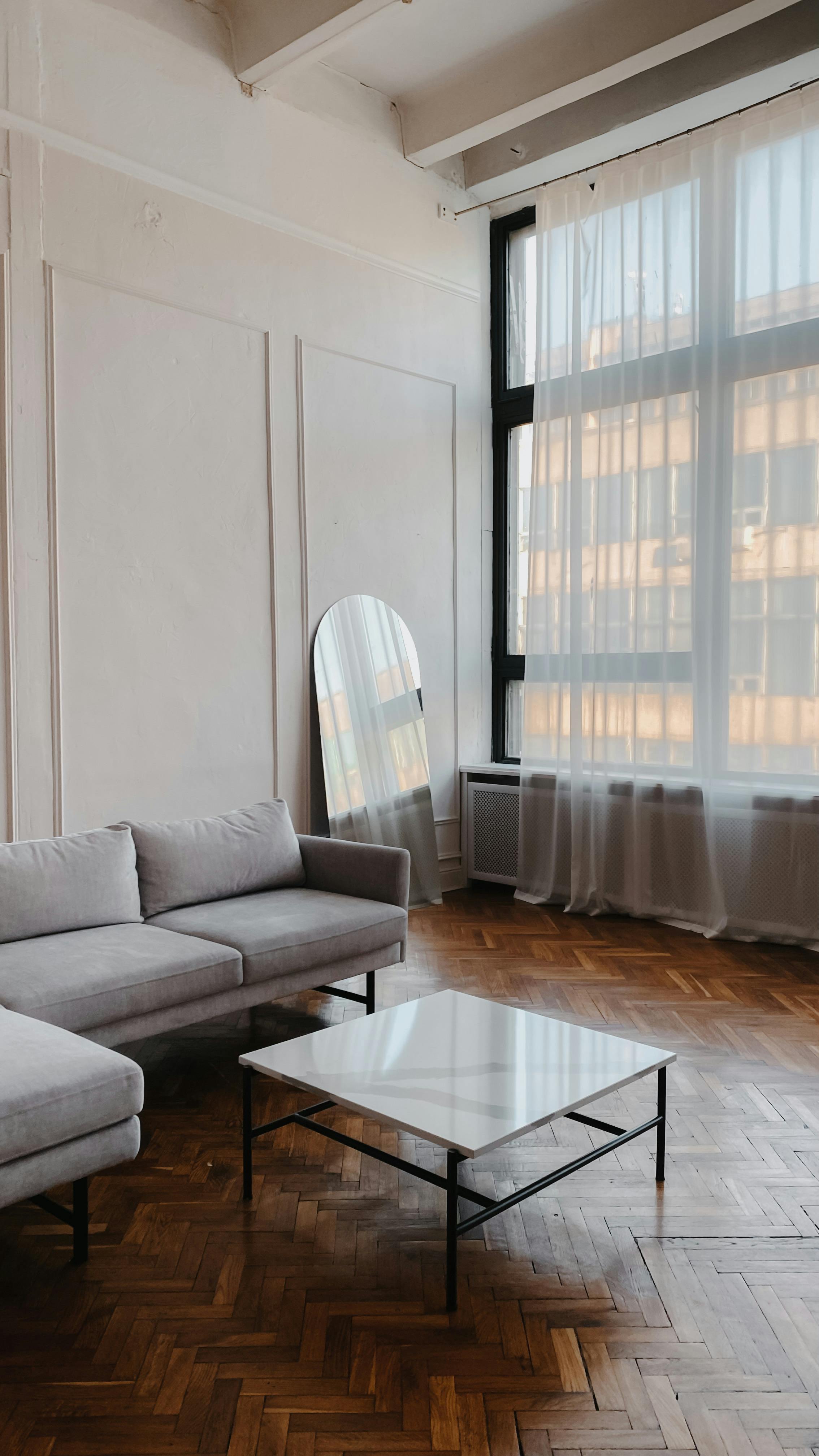 Elegant minimalist living room with large windows and cozy furnishings.