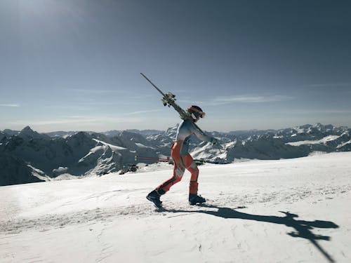 Man Carrying Skis in Snowy Mountains