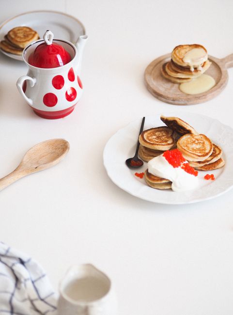 A beautifully styled pancake breakfast with fresh cream and berries on a minimalist table setting.