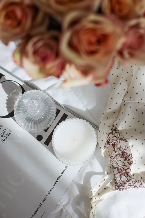 Free A cozy still life arrangement with roses, candle, and lace fabric. Stock Photo