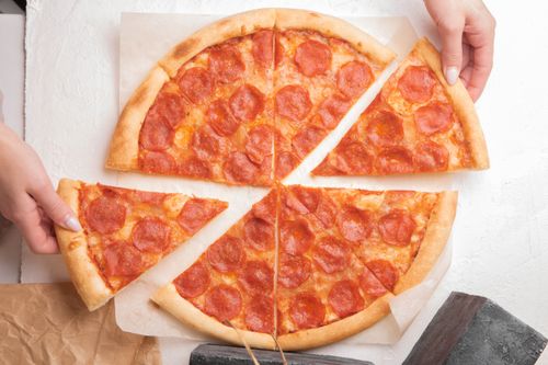 Free Top view of pepperoni pizza slices with hands holding pieces, perfect for food and culinary projects. Stock Photo