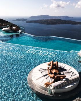 Woman lounging by the infinity pool overlooking the Aegean Sea in Megalochori, Greece.