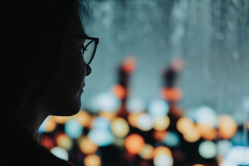 Free Silhouette of a woman with glasses against a bokeh light background, creating an artistic mood. Stock Photo