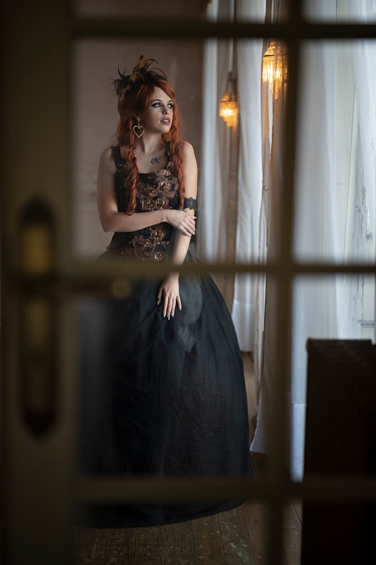 Woman In Black Gown Standing Near Window