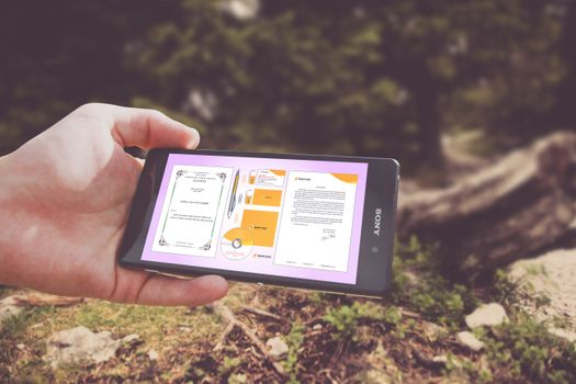 Person holding a smartphone displaying design templates outdoors in nature.