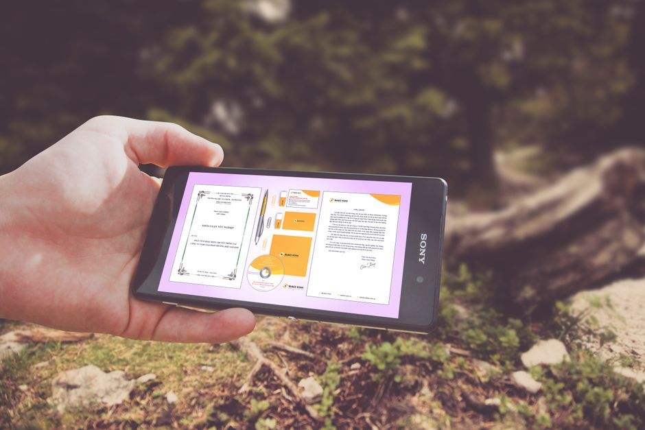 Person holding a smartphone displaying design templates outdoors in nature.