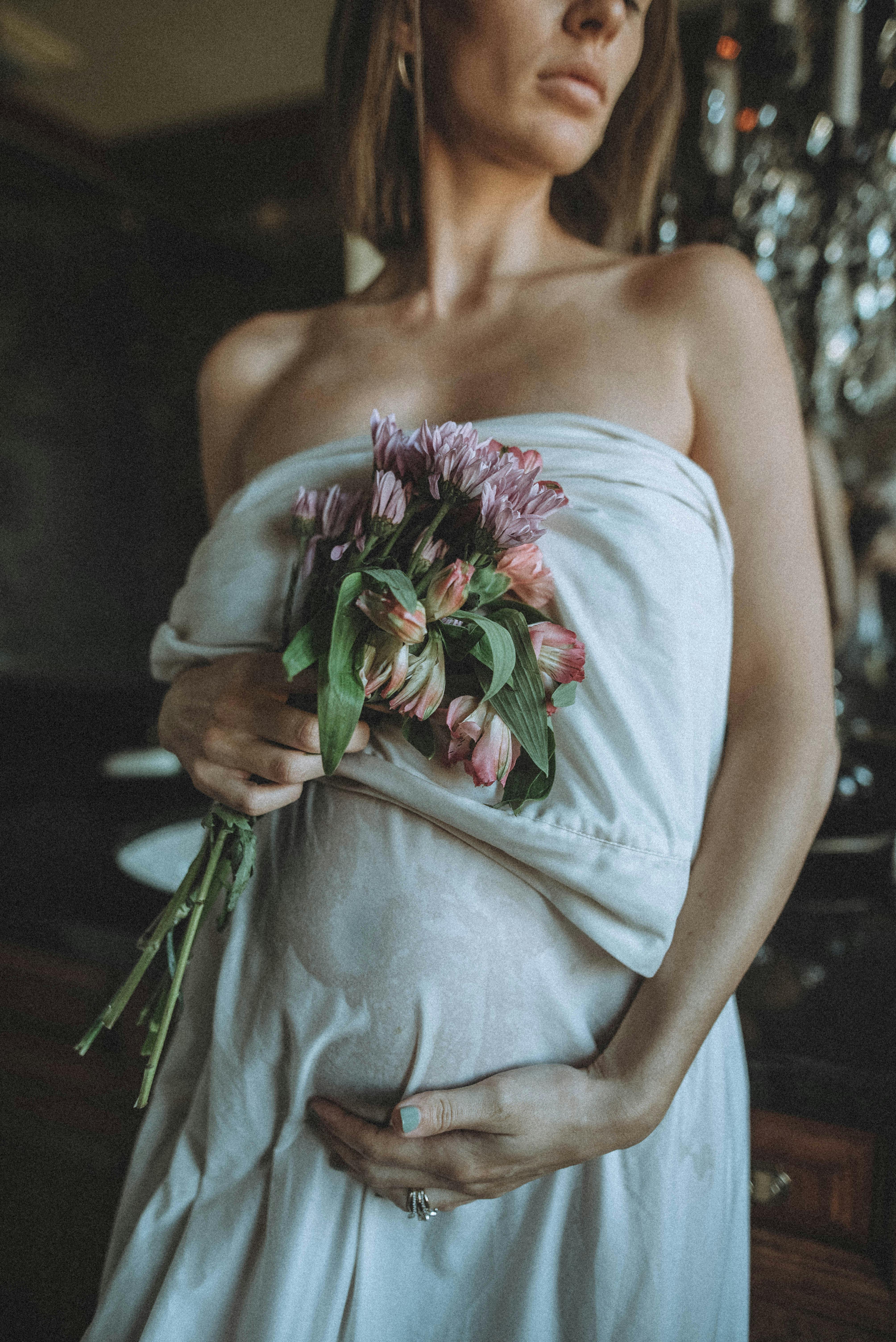 pregnant woman wearing sheet holding flowers