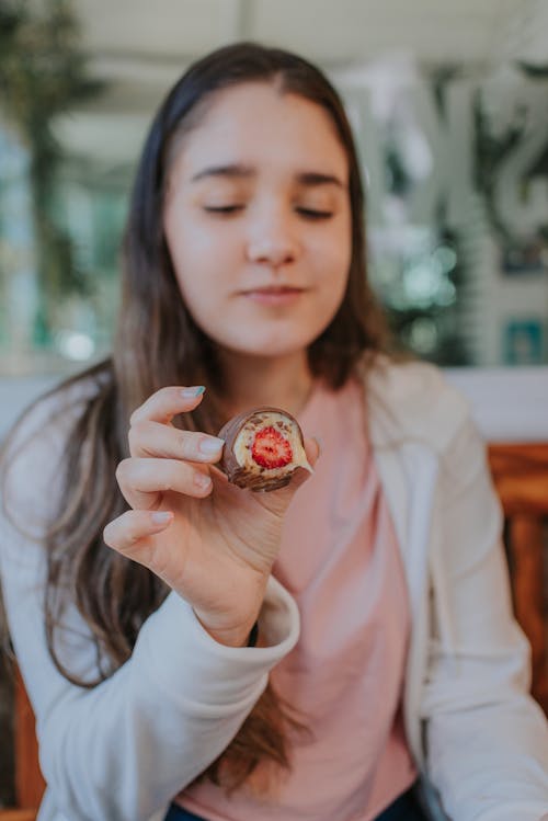 Selective Focus Photo of a Girl Holding a Dessert with a Strawberry