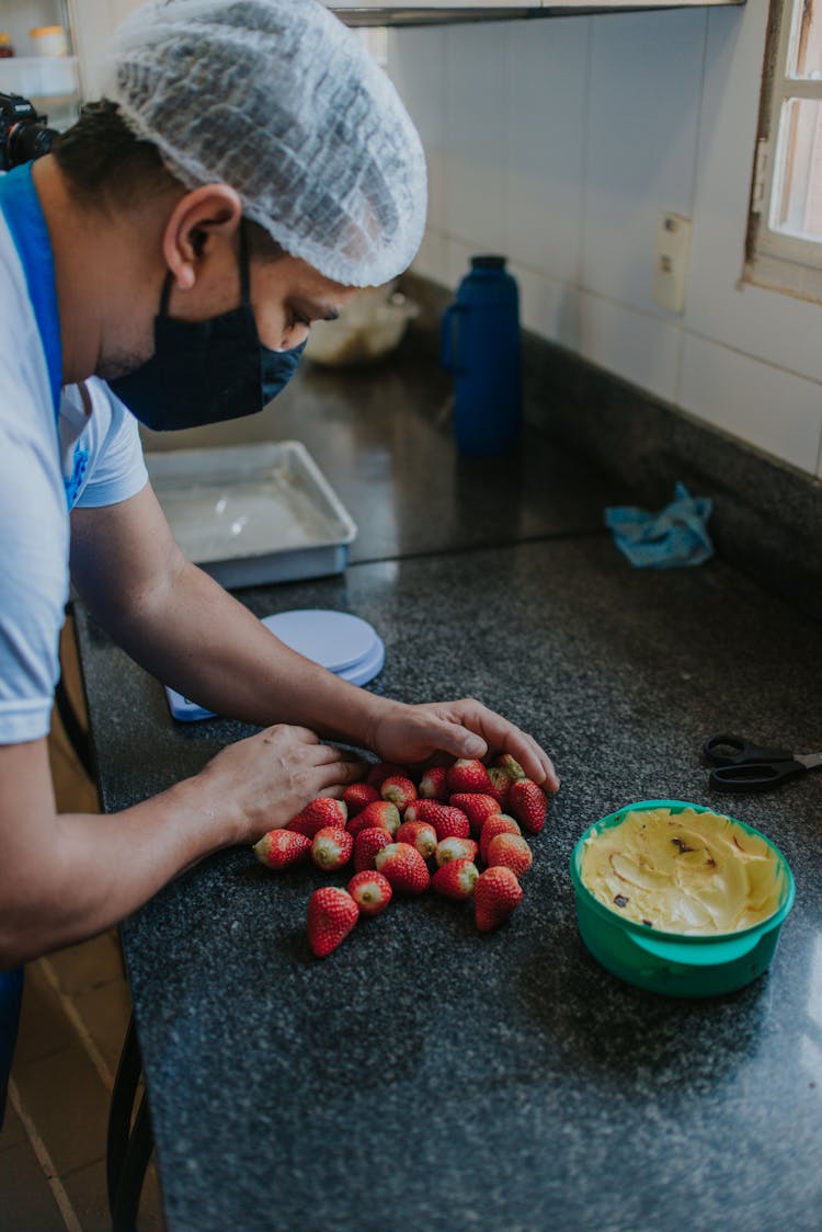 Man Gathering Fresh Strawberries On Counter