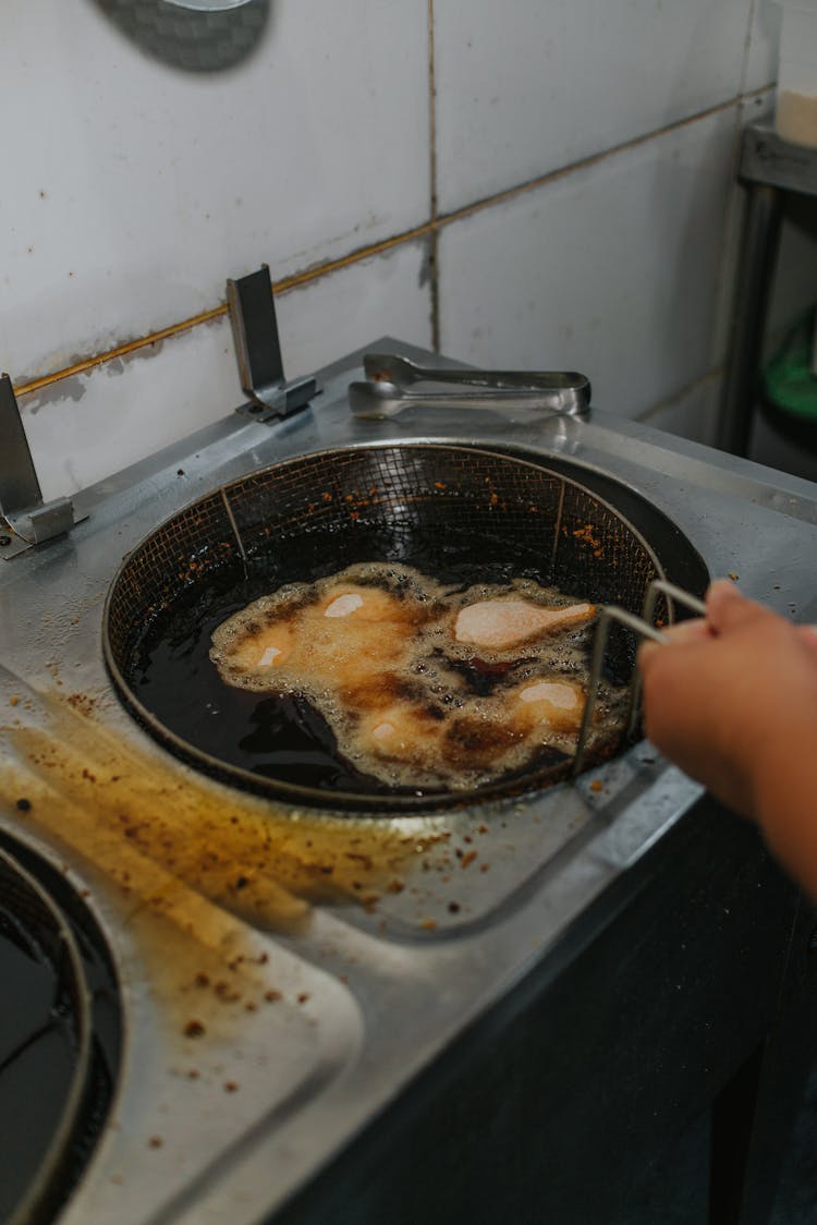 A Person Deep Frying Chicken