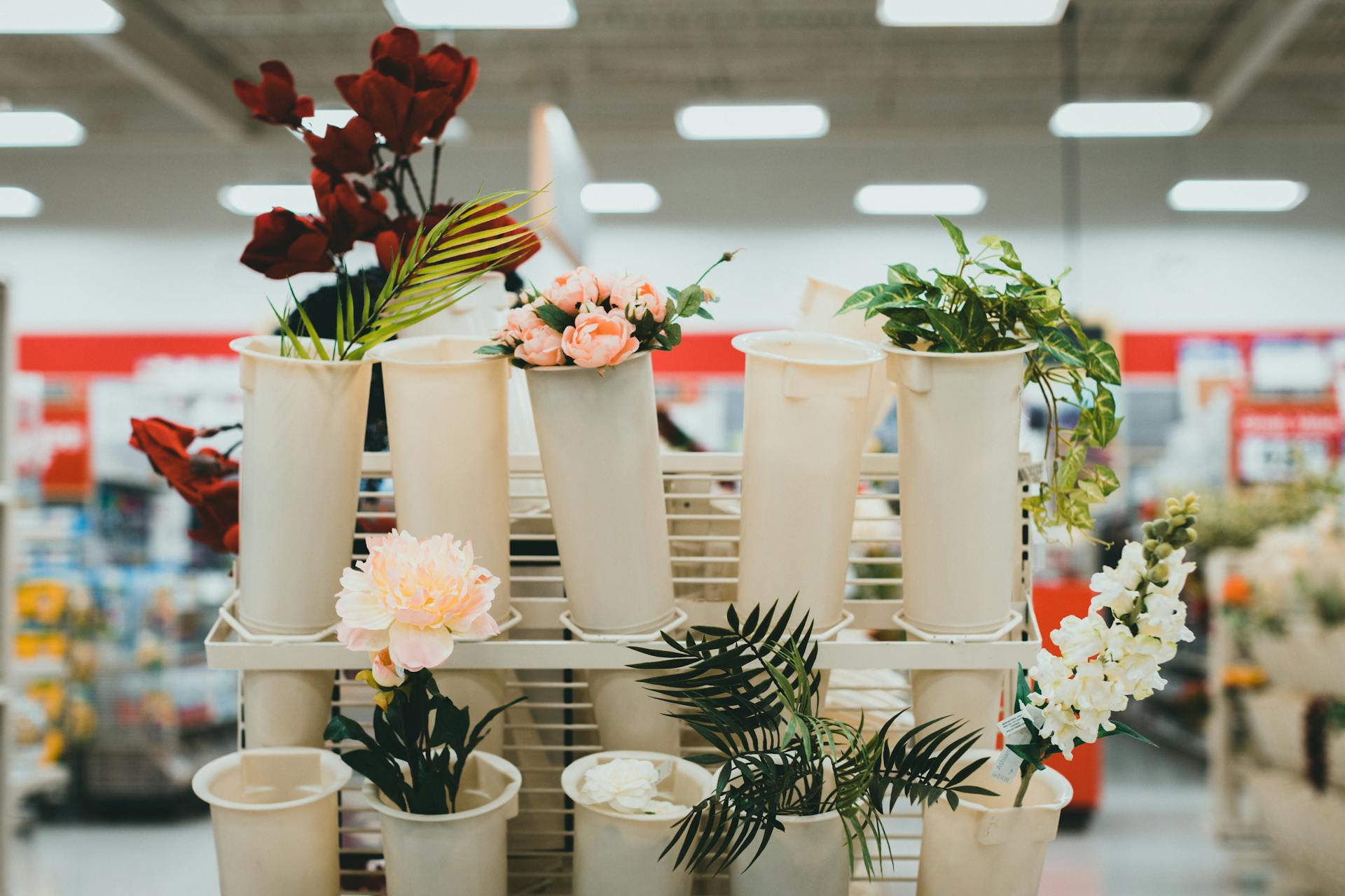 Artificial flowers in display buckets at a retail store aisle showcasing vibrant decor options.