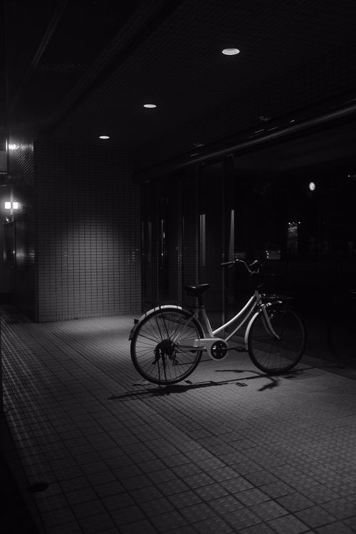 Free Moody black and white image of a solitary bicycle under streetlight in a city at night. Stock Photo