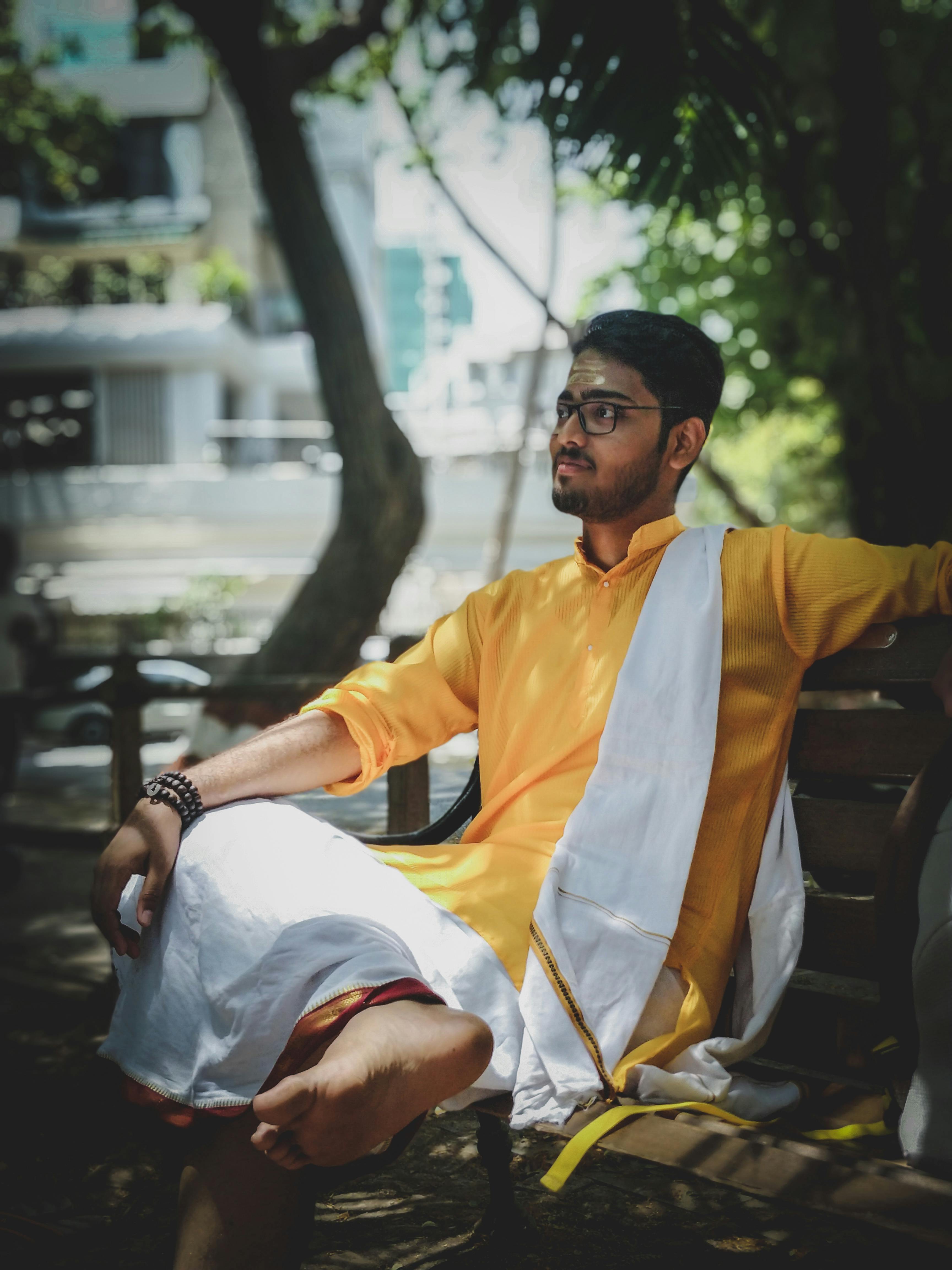 Man Wearing Yellow And White Suit Sitting On Bench Free Stock Photo