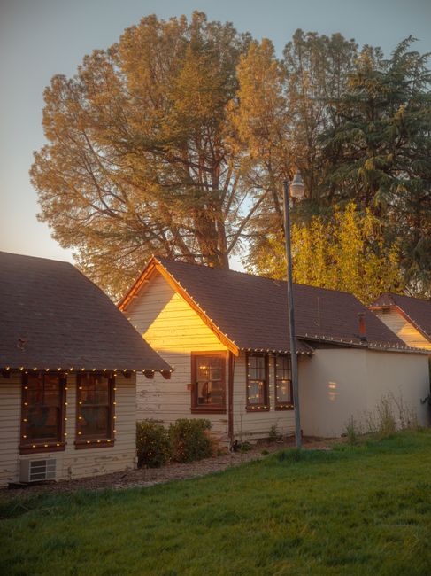 Charming village houses illuminated by sunset glow and soft lights, surrounded by lush greenery.